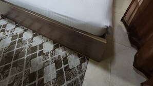 A bed with a wooden headboard, a bedside table, and a patterned rug. - LuLuat Al Khaleej Hotel Apartments (AL KARAMA)