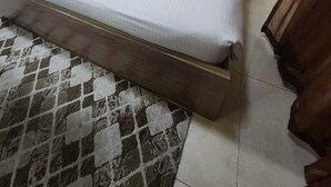 A hotel room with a bed, a nightstand, a wooden headboard, a patterned rug, and a person sitting at a table. - LuLuat Al Khaleej Hotel Apartments (AL KARAMA)