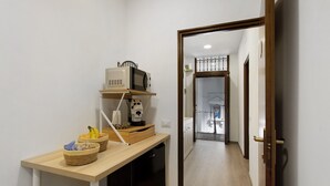 Un corridoio con angolo cottura, dotato di forno a microonde, macchina del caffè e cesti di frutta.