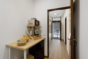 A hallway with a kitchen area, including a microwave, a coffee maker, and baskets with fruits. - Dimora Sophia Nicole: In the Heart of Catania’s Charm (Catania)