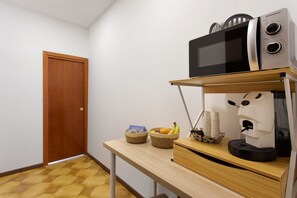 A kitchenette with a microwave, coffee machine, and a fruit basket on a wooden table. - Dimora Sophia Nicole: In the Heart of Catania’s Charm (Catania)