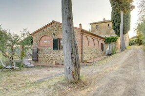 A stone building with a rustic appearance, a dirt path, and a tree in the foreground.