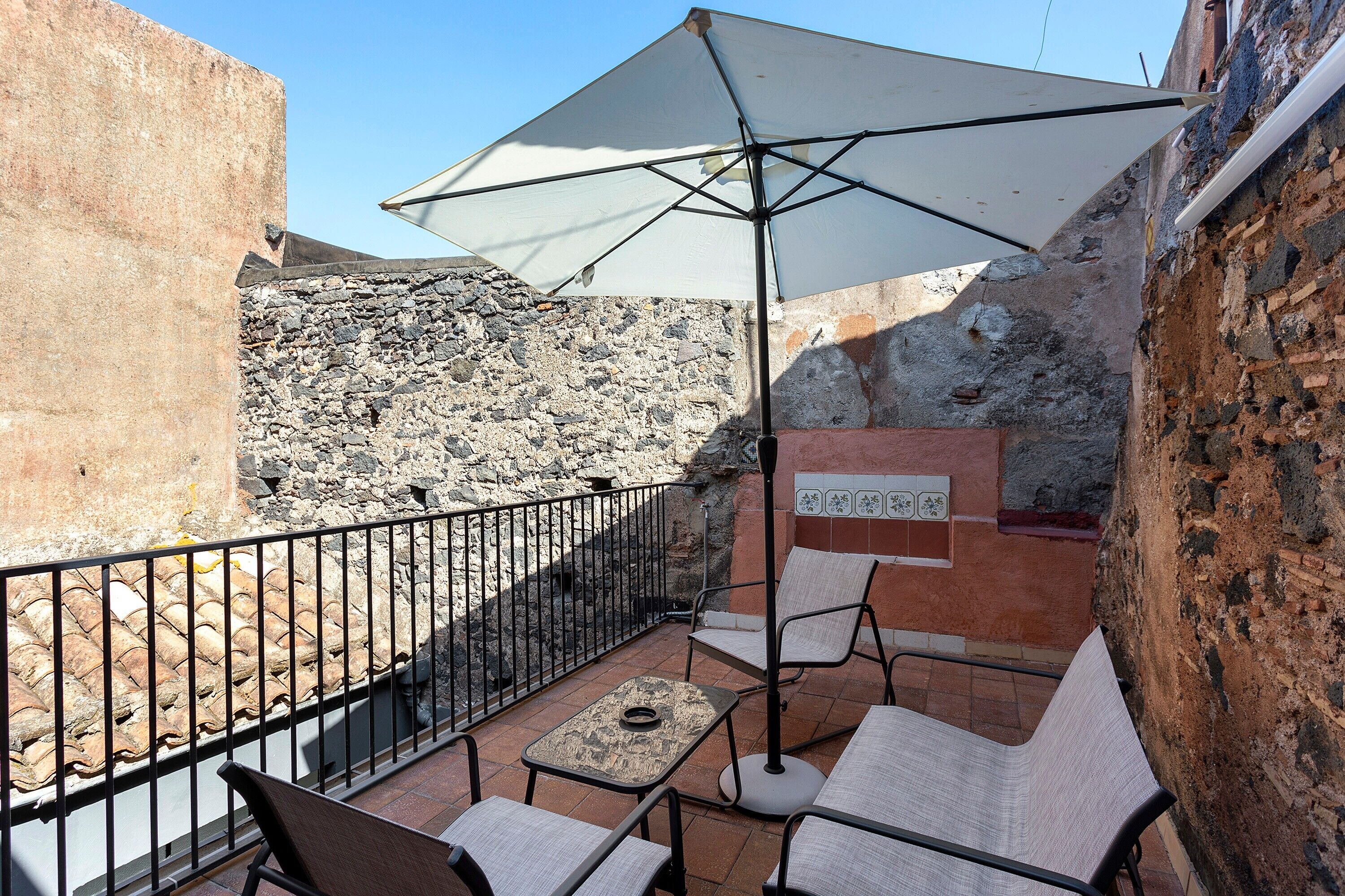 A patio with outdoor seating, a table, and a large umbrella.
