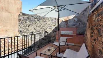 A patio with outdoor seating, a table, and a large umbrella.