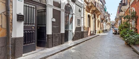 A narrow street with buildings on both sides, featuring a mix of architectural styles and a clear sky.