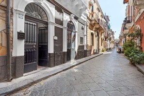 A narrow street with buildings on both sides, featuring a mix of architectural styles and a clear sky. - Dimora Sophia Nicole: In the Heart of Catania’s Charm (Catania)