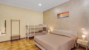 A bedroom with a bunk bed, a bedside table with a lamp, a mirror, and a painting on the wall.