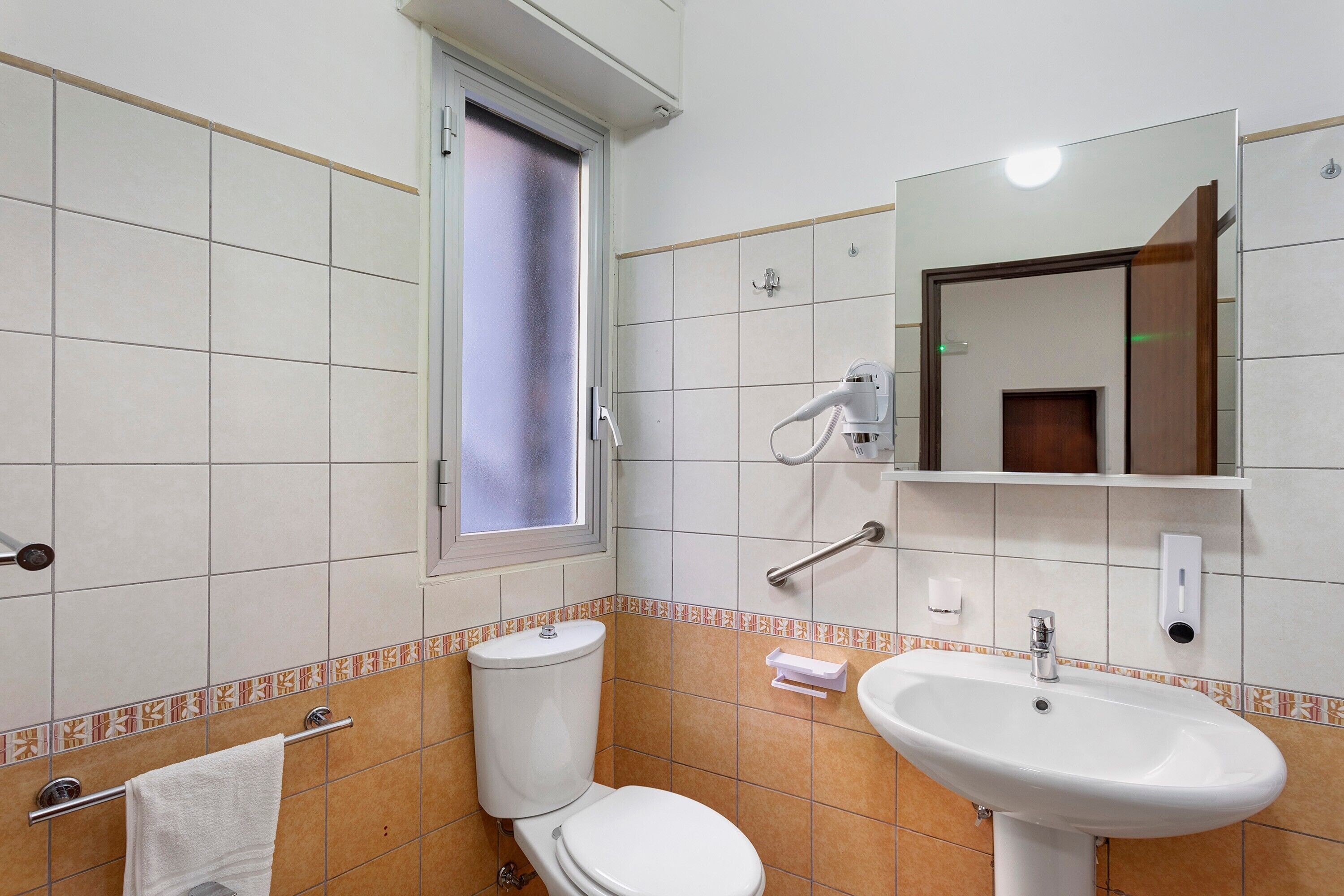 A bathroom with a toilet, sink, and a window.