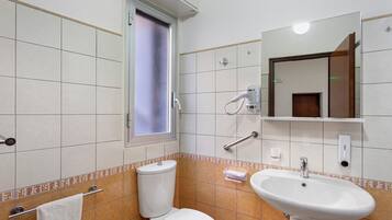 A bathroom with a toilet, sink, and a window.