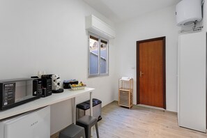 A compact kitchen with a microwave, coffee maker, and a small refrigerator. There's a window above the counter and a door to the right. - Dimora Sophia Nicole: In the Heart of Catania’s Charm (Catania)