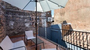 Un área de estar al aire libre con una mesa, sillas y un paraguas grande, además de un muro de ladrillo.