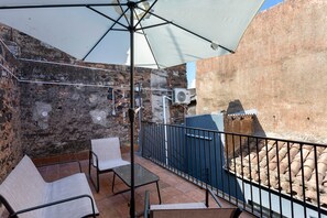 An outdoor seating area with a table and chairs, a large umbrella, and a brick wall. - Dimora Sophia Nicole: In the Heart of Catania’s Charm (Catania)
