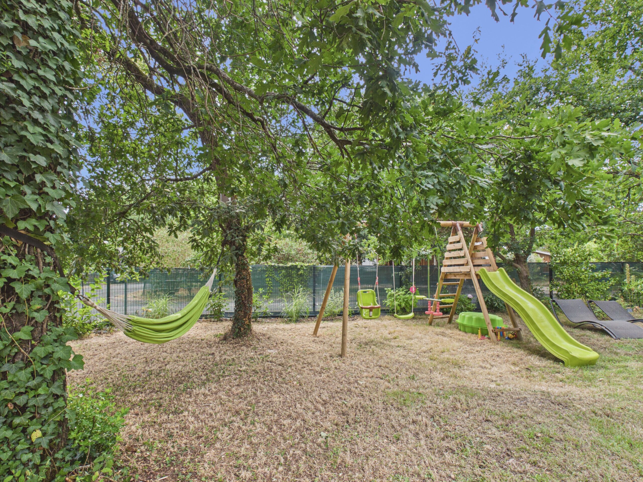 A playground with a slide, swings, and a hammock.