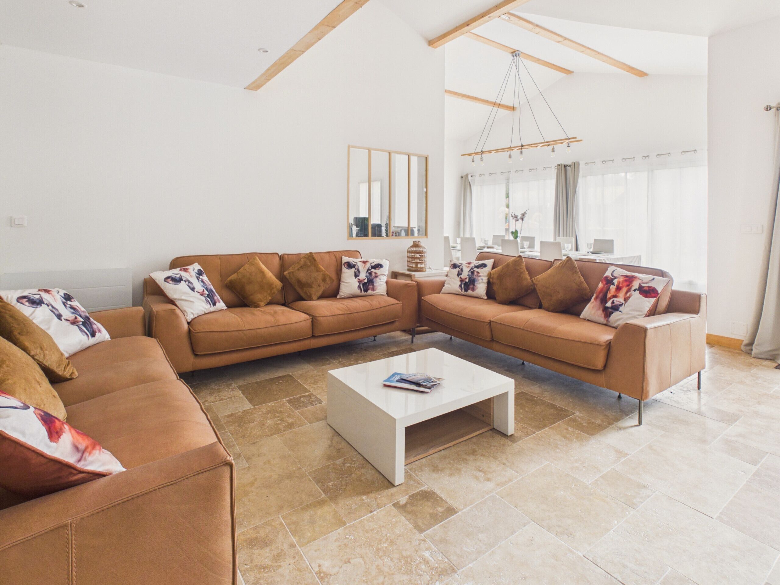 A modern living room with a sectional sofa, a coffee table, and a dining area in the background.