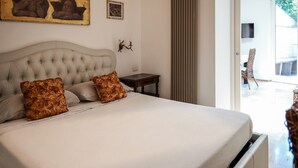 A bedroom with a large bed, two decorative pillows, a small bedside table, a wall-mounted TV, and a view of the outside. - Apartment in a Villa with a Garden (Roma)