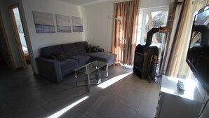 A living room with a sofa, a coffee table, a fireplace, and a TV. - Moderner Bungalow mit Terrasse im Ferienpark Mirow (Granzow)