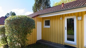 A yellow building with a red-tiled roof, a small window, and a door. - Moderner Bungalow mit Terrasse im Ferienpark Mirow (Granzow)