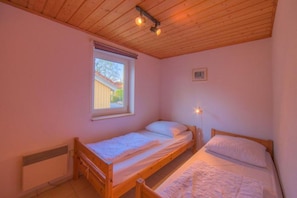 Ein kleines Zimmer mit einem Einzelbett, Holzboden und einem Bild an der Wand.