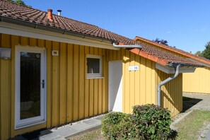 Ein gelbes Gebäude mit einem Ziegeldach, einer Tür und einem Fenster.