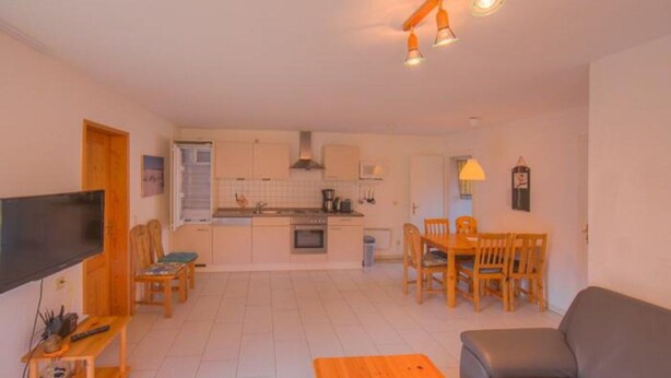 A compact living space with a kitchenette, dining area, and seating. - Komfortabler Doppelbungalow mit Terrasse im Ferienpark Mirow (Granzow)