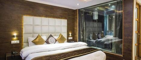 A modern bedroom with a large bed, a glass shower enclosure, and a wooden accent wall.