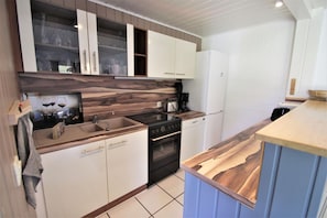 Eine Küche mit weißen Schränken, einer Holzausziehtafel, einem Herd und einem Geschirrspüler.