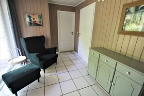 Um quarto com uma cadeira, uma mesinha, um armário e uma porta.