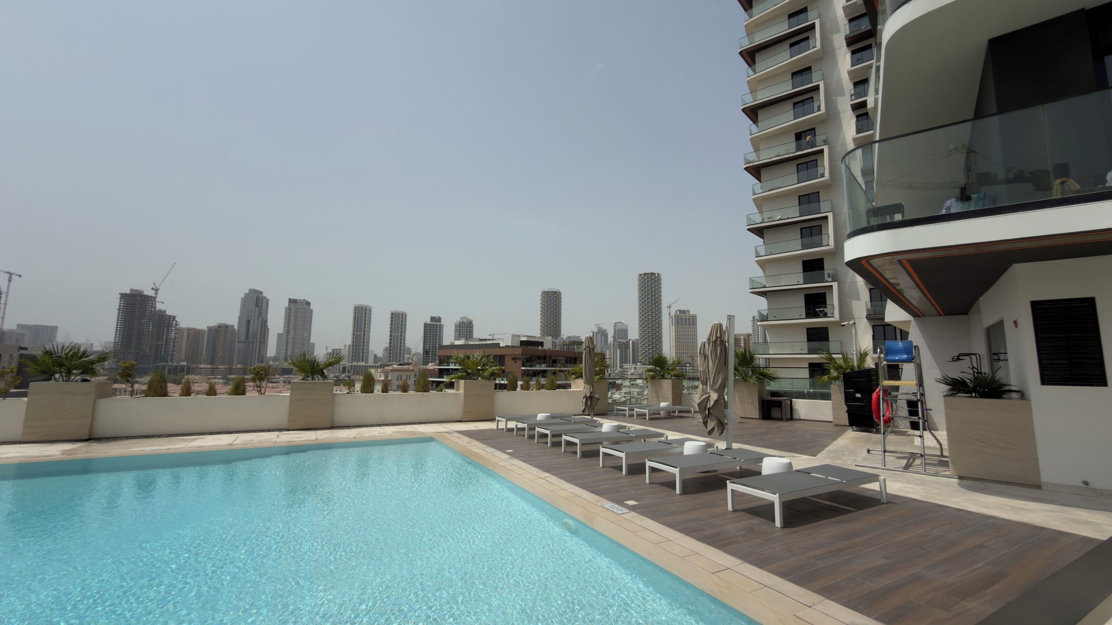 Un espace piscine sur le toit, avec des chaises longues et une vue panoramique sur la ville.