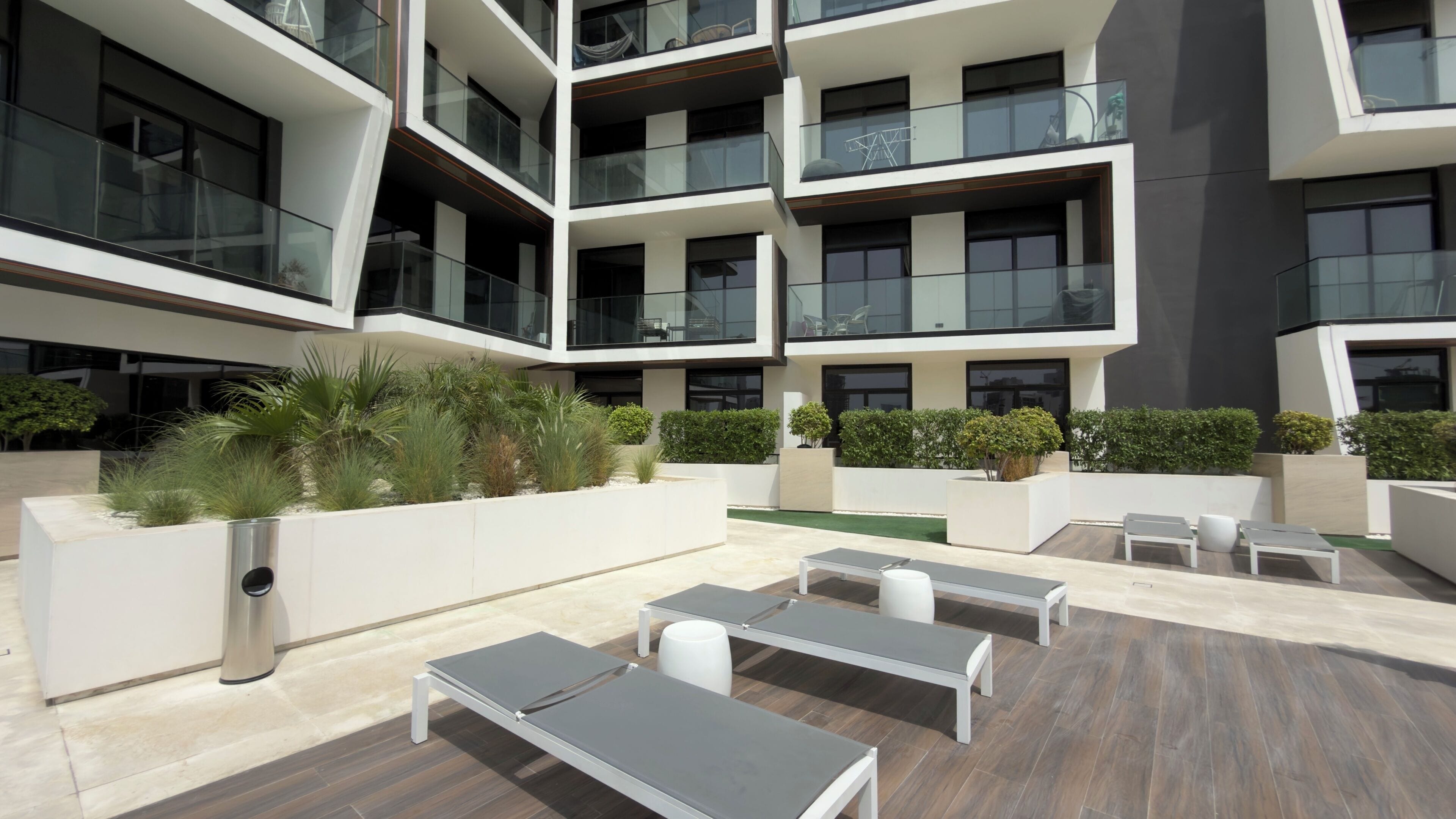A modern outdoor lounge area with multiple seating options and planters.