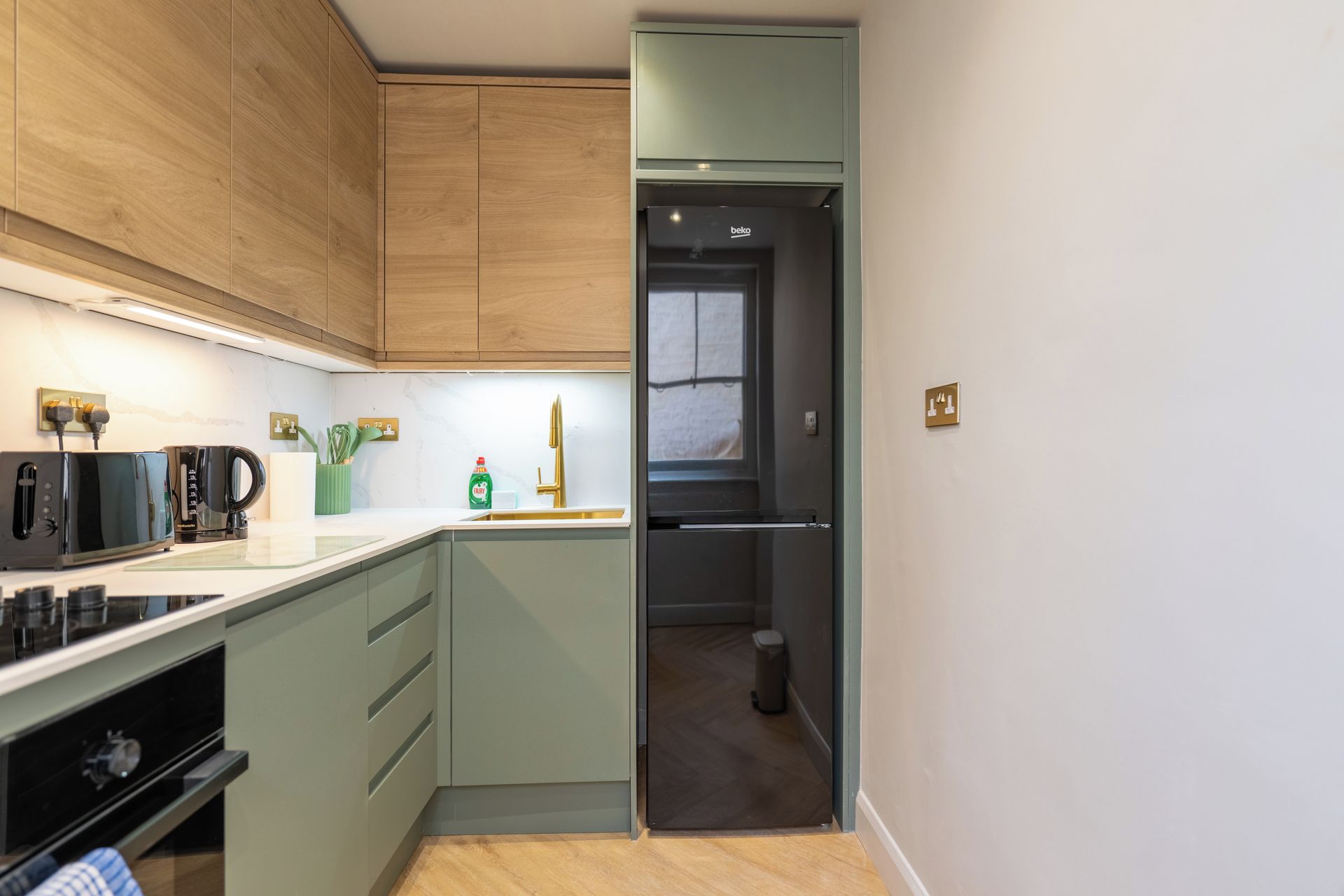 A modern kitchen with wooden cabinets, a built-in oven, and a black refrigerator.