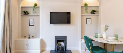 Una sala de estar moderna con chimenea, un televisor de pantalla plana y un comedor con sillas verdes.