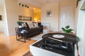 A turntable in a living room with a sofa and a plant in the background. - City centre modern apartment- By Vichy (Liverpool)