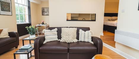 A modern living room with a brown leather sofa, a coffee table, and a large window.