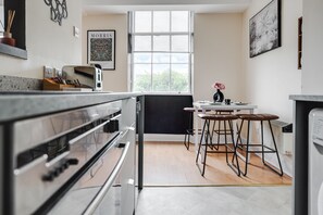 Eine moderne Küche mit großem Fenster, Barhocker und Kühlschrank.