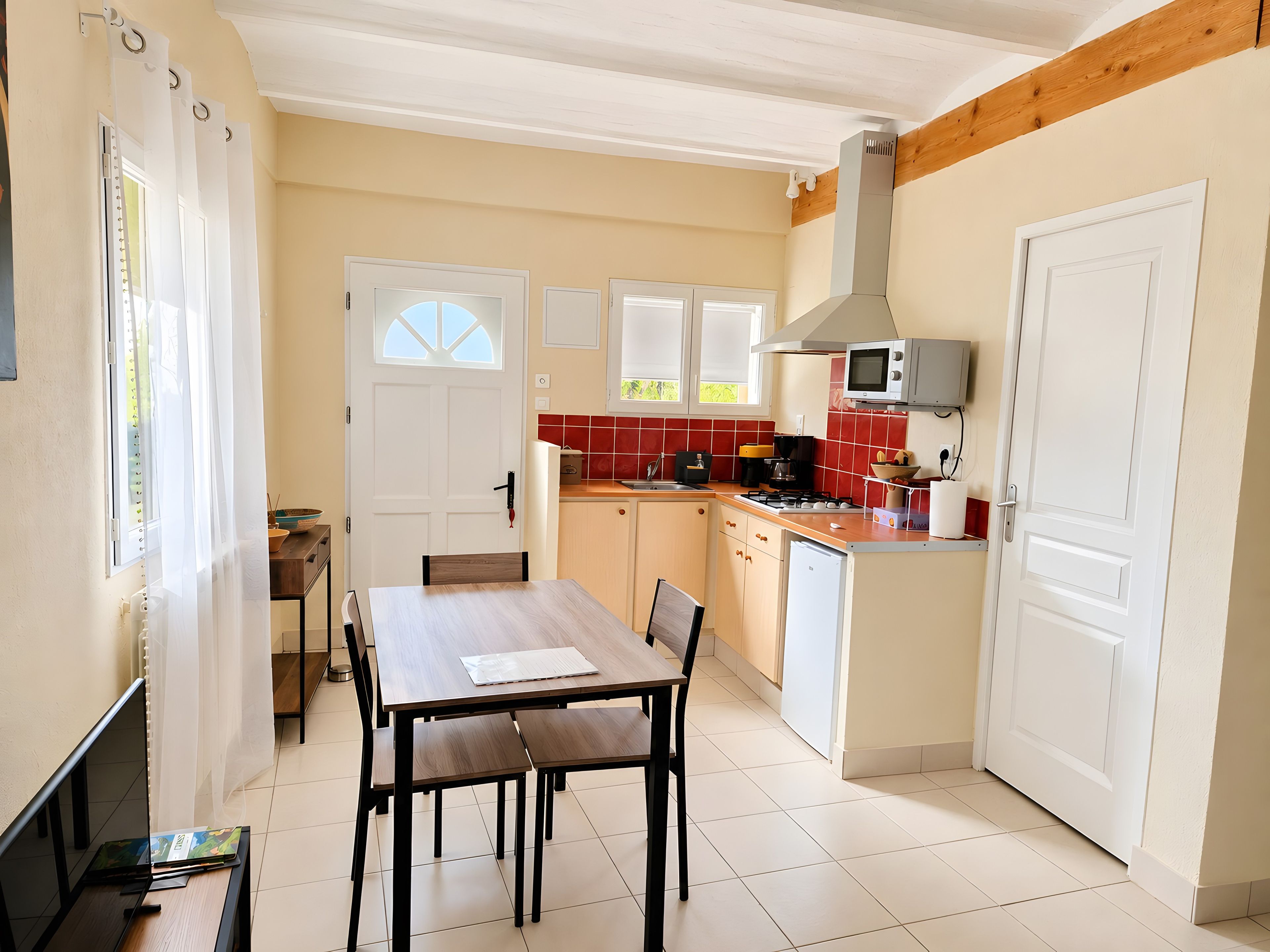 A compact kitchen with a dining area, white cabinets, a microwave, and a small refrigerator.