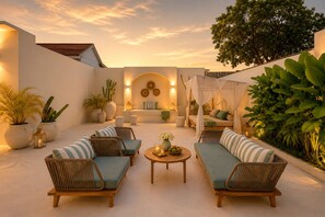 An outdoor seating area with wicker furniture, a round table, and potted plants. - Private Pool Villa - Central Canggu (Canggu)