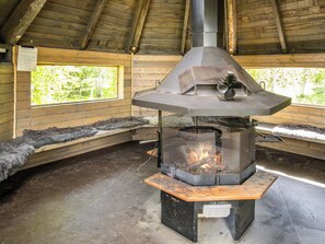 A wood-burning stove with a chimney, surrounded by wooden benches and a window with a view of greenery. - Ylläs 1 by Interhome (Ylläsjärvi)