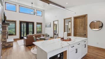 A modern kitchen with a large island, wooden flooring, and a dining area with a sofa and chairs.
