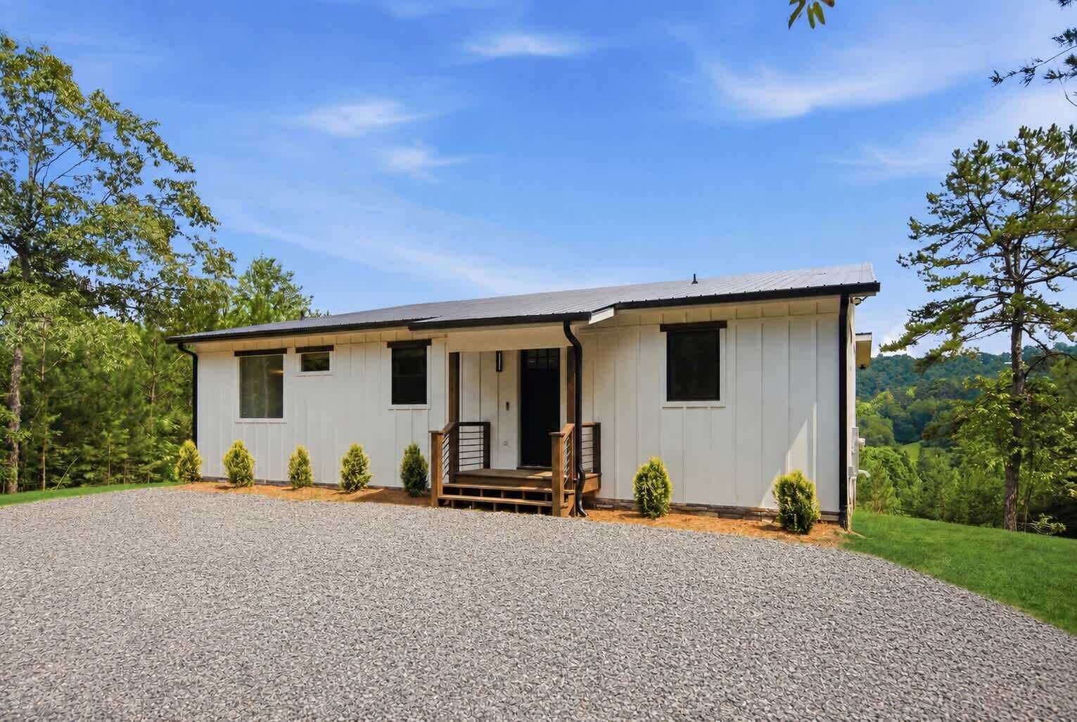 A single-story building with a gravel driveway, a front porch, and a small garden area.