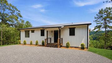 A single-story building with a gravel driveway, a front porch, and a small garden area.