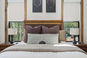 Quarto com uma cama grande, duas mesas de cabeceira, uma cabeceira de madeira e quadros na parede.