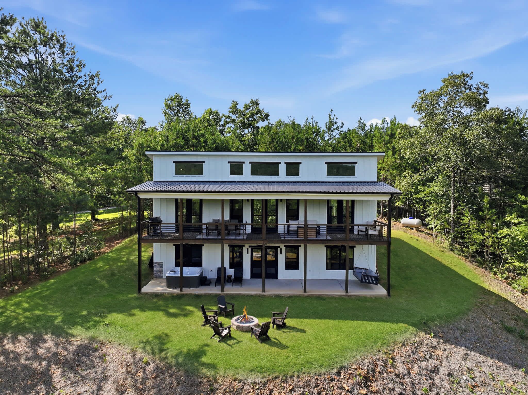 A two-story house with a balcony, a fire pit, and a well-maintained lawn.