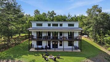 A two-story house with a balcony, a fire pit, and a well-maintained lawn.