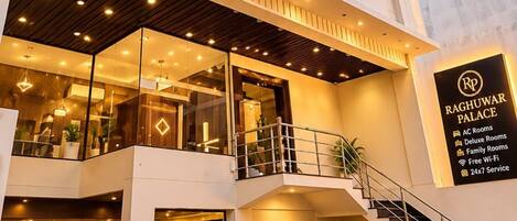 A modern hotel with a central atrium, multiple floors, and a staircase leading to the entrance.