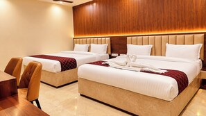 Quarto de hotel com duas camas, cabeceira de madeira, piso de mármore e uma mesa de jantar com cadeiras.