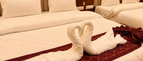 A hotel room with two beds, each with white linens and a red patterned bed runner.