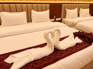 Una camera d'albergo con due letti, entrambi con lenzuola bianche e una coperta a balze rossa.