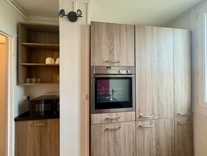 Une cuisine moderne avec des meubles en bois, un four encastré et un four à micro-ondes.