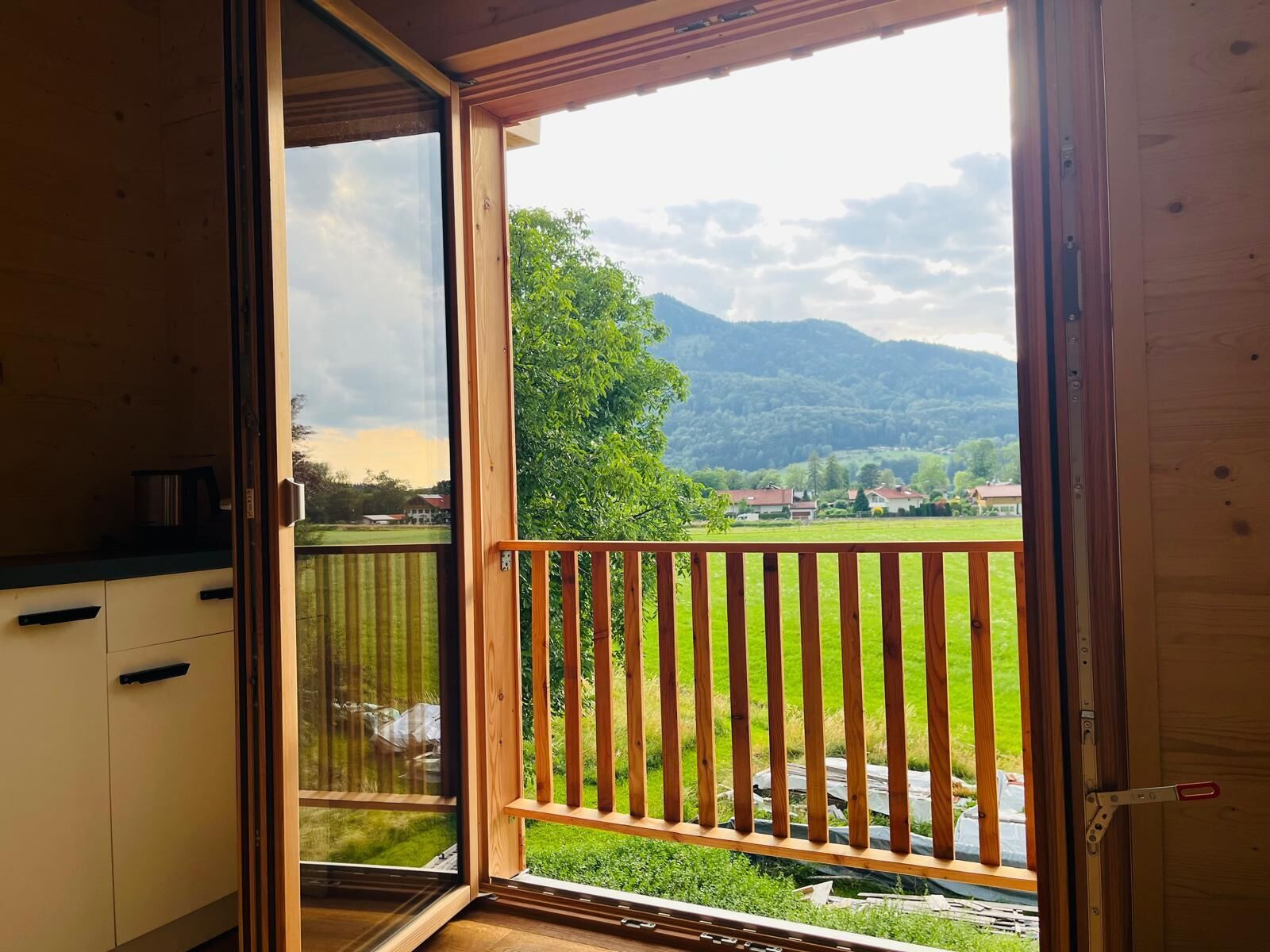A room with a wooden door leading to a balcony with a wooden railing.