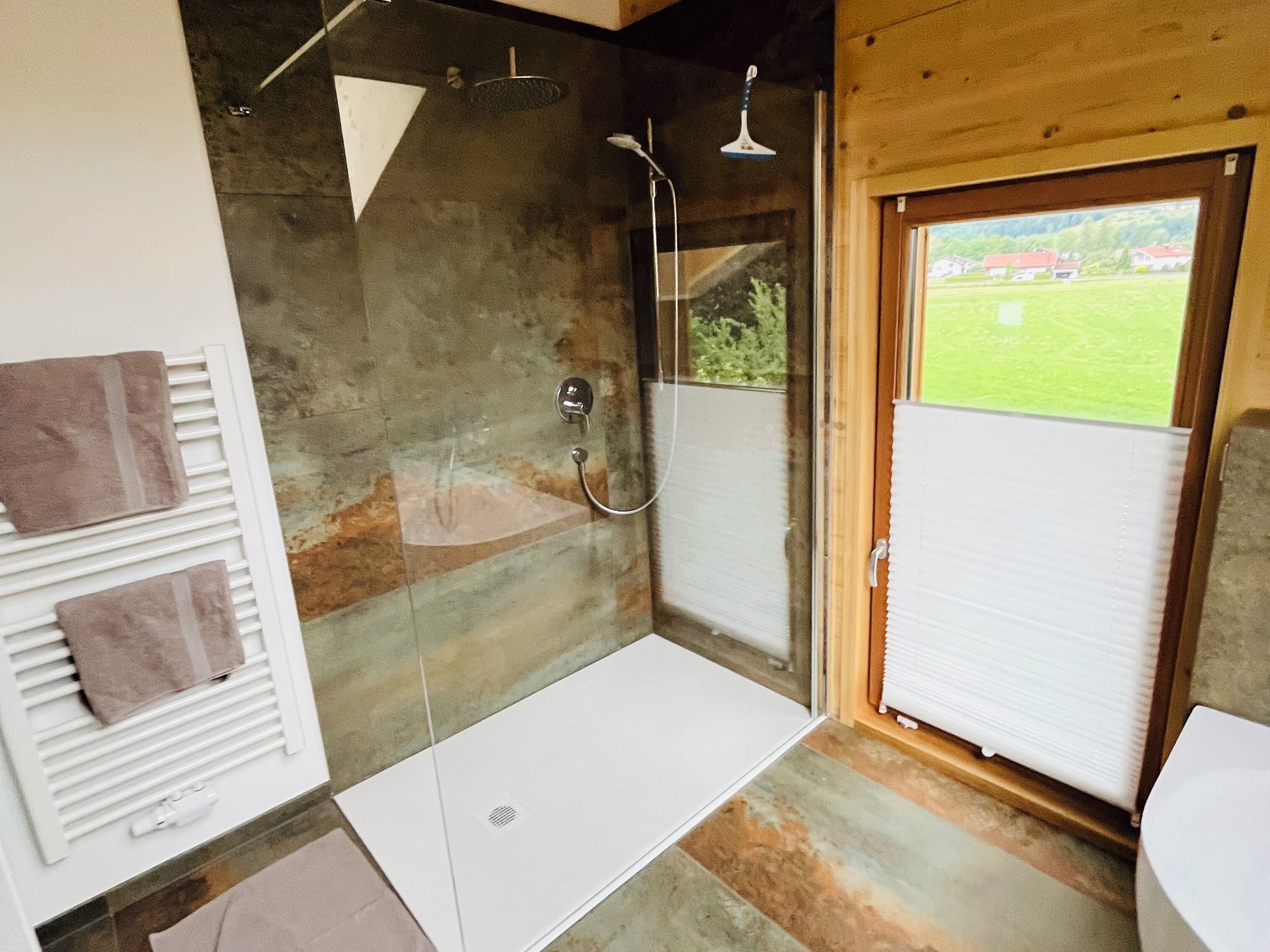 Een moderne badkamer met een glazen douchecabine, een wit bad en een toilet.
